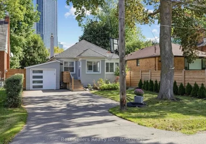 A brick bungalow with a long driveway and mature trees